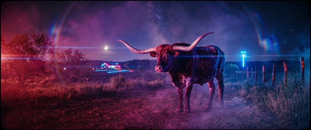 A Texas Longhorn steer standing on a ranch road at night, lit by magenta and cyan light, under a crescent moon and the Milky Way.